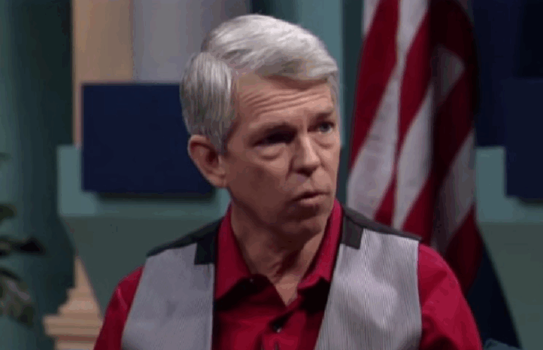 David Barton is shown sitting and looking to the right wearing a gray vest over a red button-down shirt. He appears to be speaking. He has been appointed as a content advisor by a member of the Texas SBOE.